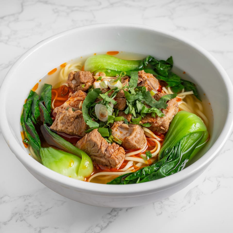 Nana Noodle House beef noodle soup with bok choy, cilantro, and scallions in a white bowl.