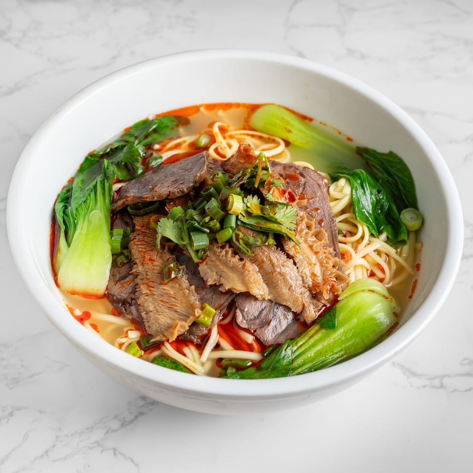 A bowl of Nana Noodle House's beef noodle soup with bok choy, tripe, and green onions.
