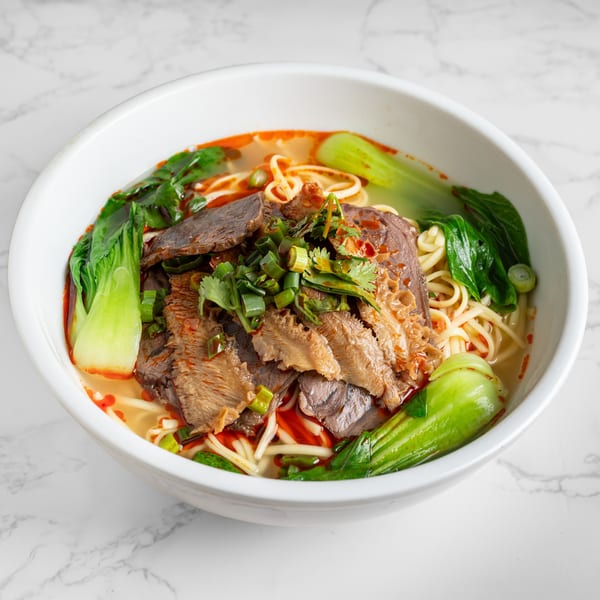 A bowl of Nana Noodle House's beef noodle soup with bok choy, tripe, and green onions.