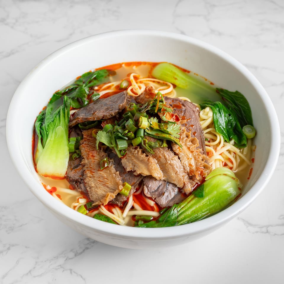 A bowl of Nana Noodle House's Chinese beef noodle soup with bok choy and green onions.