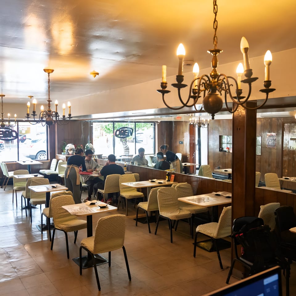 Interior of Nana Noodle House, showing dining tables, chandeliers, and patrons enjoying meals.