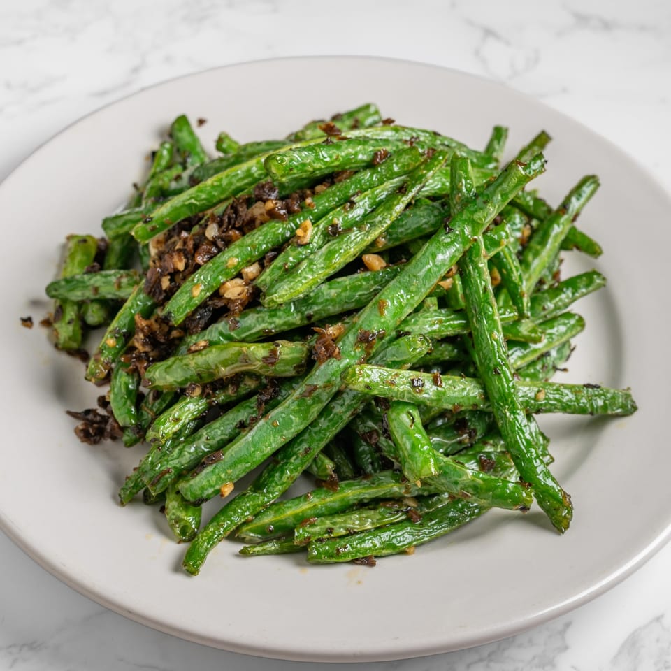 Nana Noodle House's stir-fried green beans with minced garlic and dark sauce on a white plate.